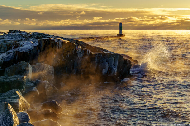 Image of a marker light house during sunrise with rocks