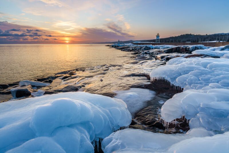 Image of ice and snow on rocks along lake superior at sunset