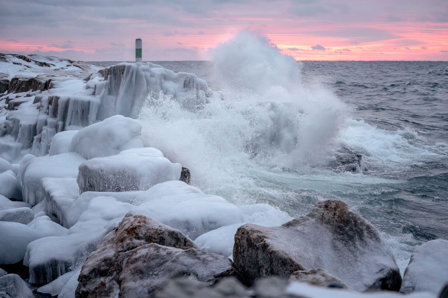 Image of Waves Crashing against rocks during sunrise.